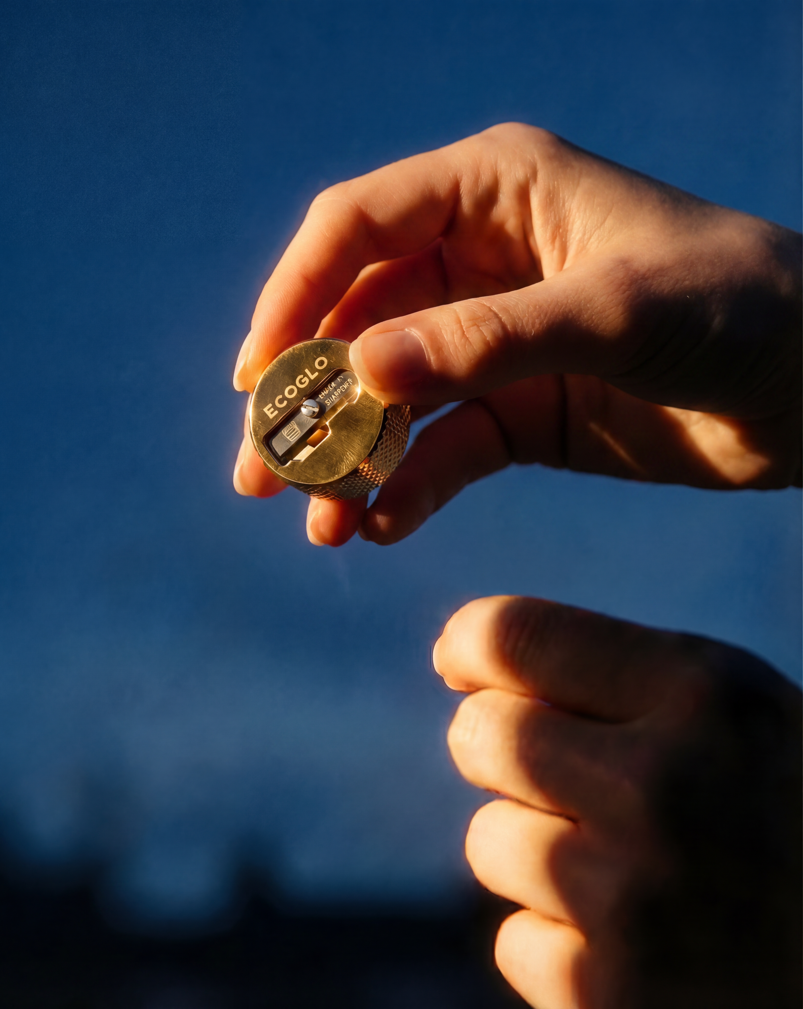 A close-up of a hand holding a small gold-colored EcoFlow battery charger or battery module against a dark blue background.