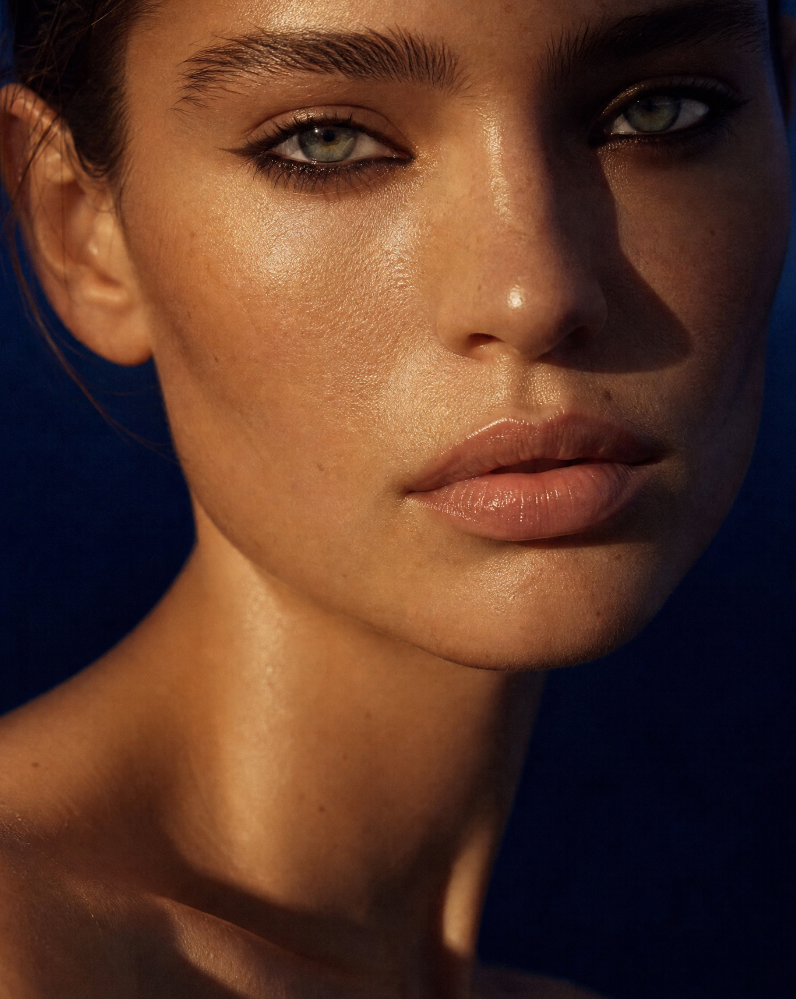A close-up portrait of a woman with dramatic warm lighting and a dark blue background.